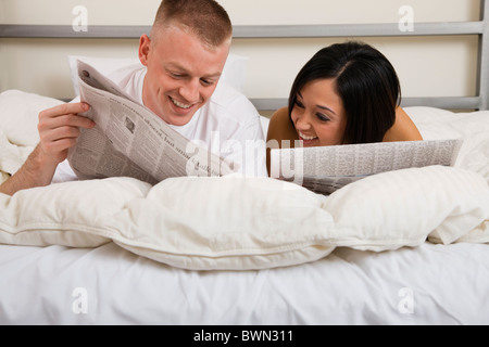 États-unis, Illinois, Metamora, Couple Lying in Bed and reading newspaper Banque D'Images