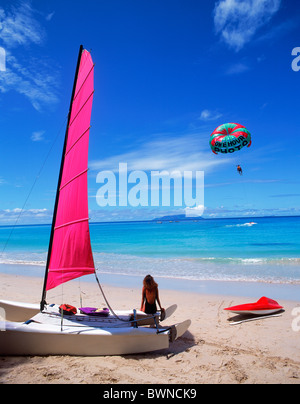 Femme assise sur catamaran sur plage en regardant le parapente sur l'île de Mahé aux Seychelles Banque D'Images