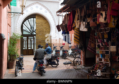 Les jeunes hommes sur un cyclomoteur à un souk à côté d'un riad de luxe à Marrakech, l'Afrique du Nord Banque D'Images