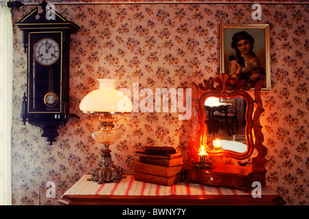 De vieux livres empilés sur un bureau avec lampe, miroir, horloge, bougie et du mur de papier dans le pays accueil en Suède Banque D'Images