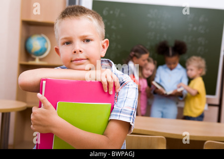 Image de smart lad looking at camera sur fond de camarades de lecture Banque D'Images