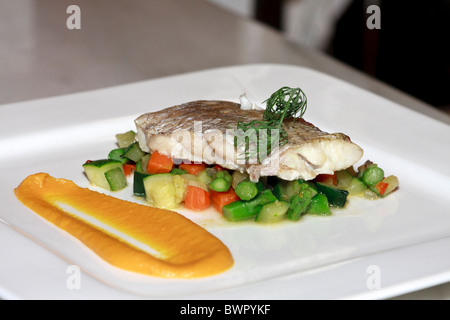 Un filet de poisson sur un lit de légumes prêts à être servis dans un restaurant. Banque D'Images