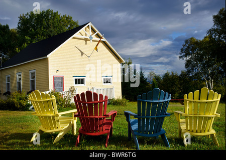 Chaises Adirondack en jaune, rouge et bleu sur la baie des Chaleurs Banque D'Images