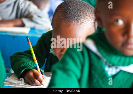 Les bidonvilles de Mathare de garçon écrit à Maji Mazuri centre et école, Nairobi, Kenya Banque D'Images