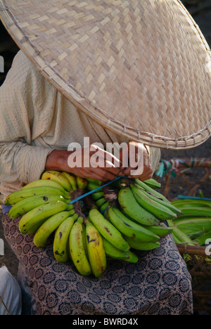 Dans un marché de village traditionnels, à Bali, en Indonésie, une femme dans un chapeau conique prépare les bananes à la vente. Banque D'Images