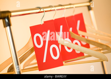 Image de plusieurs cintres en bois avec des étiquettes rouges montrant remise sur eux Banque D'Images