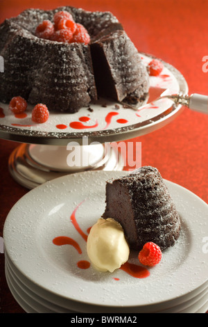 Gâteau fondant au chocolat avec coulis de framboises. Servi avec de la glace à la vanille. Banque D'Images