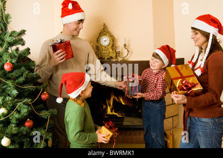 Portrait de parents et de fils wearing santa hats avec présente dans les mains Banque D'Images