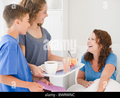 Les enfants hispaniques porter mère petit-déjeuner au lit Banque D'Images