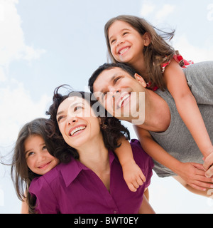 Smiling parents giving daughter's piggyback ride Banque D'Images