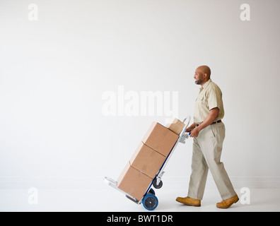 African American deliveryman poussant camion de main avec des cases Banque D'Images