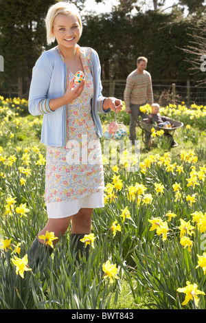 Woman Hiding Oeufs de Pâques décorés de chasse parmi les Jonquilles Banque D'Images