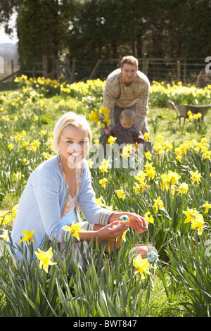 Woman Hiding Oeufs de Pâques décorés de chasse parmi les Jonquilles Banque D'Images