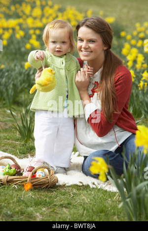 Mère et fille dans le champ de la Jonquille avec oeufs de Pâques décorés Banque D'Images