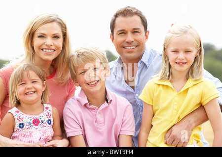 Famille assis sur des bottes de paille dans les champs récoltés Banque D'Images
