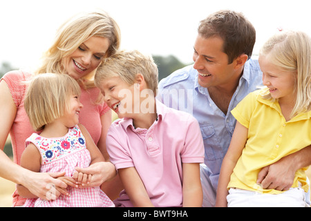 Famille assis sur des bottes de paille dans les champs récoltés Banque D'Images