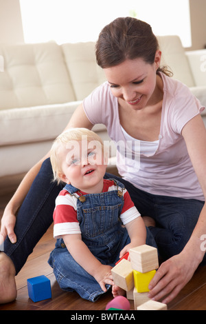 Mère et son fils jouer avec des blocs de couleur à la maison Banque D'Images