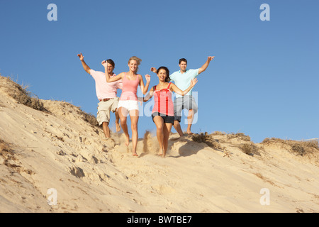 Groupe, amis plage vacances courant le long des Dunes Banque D'Images