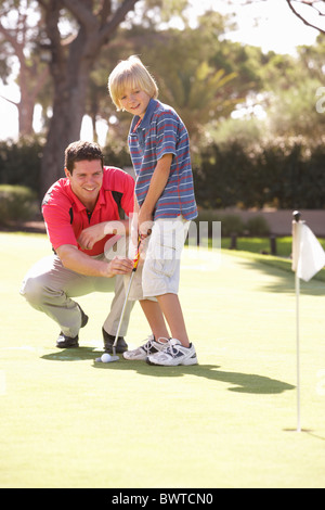 L'enseignement du père fils jouer au golf sur le putting green Banque D'Images