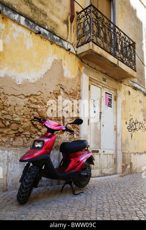 Un scooter se trouve en face d'un vieux bâtiment rustique en 2124. Banque D'Images