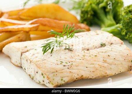 Filet de loup de mer avec brocoli et puces que gros plan sur une plaque blanche Banque D'Images