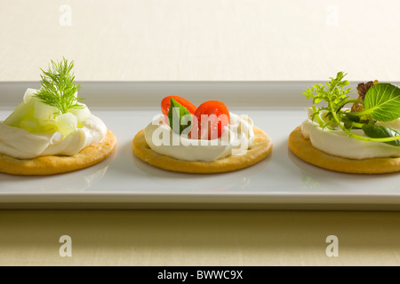 Les craquelins avec du fromage crémeux propagation, garni de tomates, basilic, concombre, aneth, mixte et de radis vert sur le dessus sur fond blanc r Banque D'Images