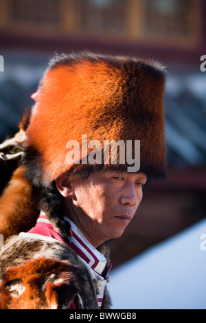 L'homme vêtu du costume traditionnel Naxi le panda rouge fur hat, Lijiang, Yunnan Province, China Banque D'Images