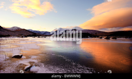 La recherche à travers un frozen lochan nah-achlaise des sommets de la chaîne de montagnes Blackmount en hiver au coucher du soleil, en Écosse, au Royaume-Uni. Banque D'Images