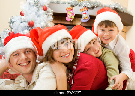 Portrait of happy family wearing Santa caps et looking at camera with smiles Banque D'Images