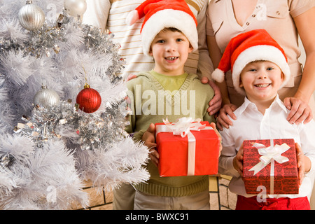 Portrait of happy frères et sœurs à Santa caps holding giftboxes en mains Banque D'Images