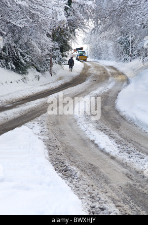 Homme marchant le long d'une chaussée couverte de neige après une forte tempête de neige. Banque D'Images