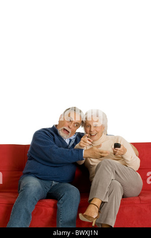 Couple de personnes âgées sur le canapé avec la télécommande du téléviseur Banque D'Images