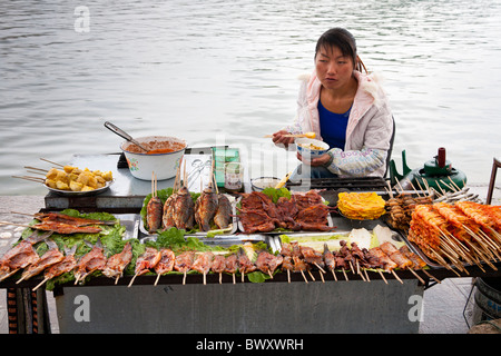 Femme vendant des aliments cuits, Île Jinsuo, près de Dali, Yunnan Province, China Banque D'Images