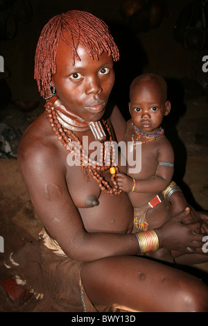 Jeune femme tribu Hamer avec bébé assis à l'intérieur de sa hutte, Boryani, vallée de l'Omo, Ethiopie Banque D'Images