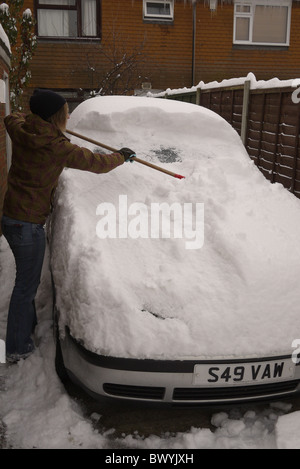 Effacement de la femme dur après de fortes chutes de neige en Angleterre Novembre 2010 voiture creuser hors de son allée coincé. Banque D'Images