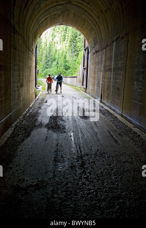 L'homme et de la femme avec leurs vélos à la fin de l'Taft Tunnel, le tunnel le plus long sur la piste d'Hiawatha, New York, USA. Banque D'Images