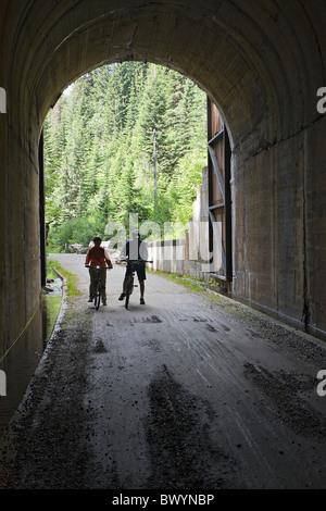 L'homme et de la femme avec leurs vélos à la fin de l'Taft Tunnel, le tunnel le plus long sur la piste d'Hiawatha, New York, USA. Banque D'Images