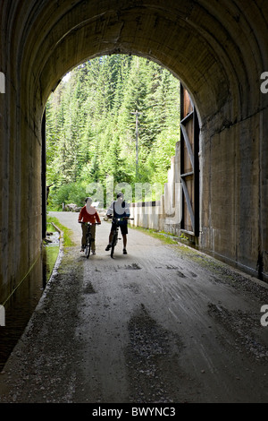 L'homme et de la femme avec leurs vélos à la fin de l'Taft Tunnel, le tunnel le plus long sur la piste d'Hiawatha, New York, USA. Banque D'Images