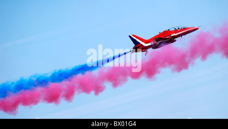 Un seul des flèches rouges hawk avec écran arrière de l'équipe et la fumée bleue volant dans la fumée rouge dirigeants - Blue Skies Banque D'Images