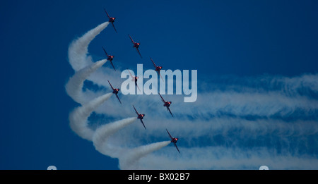 Des flèches rouges Hawks et tournant de l'équipe d'avion par l'intermédiaire de leurs traînées de fumée Banque D'Images