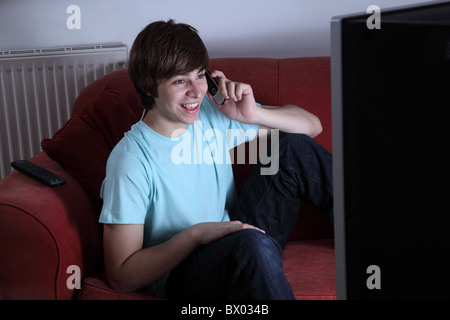 Jeune homme tenant une sourire et regarder la télévision Banque D'Images