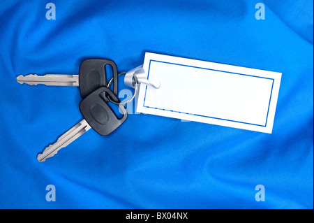 Un ensemble de nouvelles clés de voiture avec le ruban attaché à une carte vierge pour copie. Banque D'Images