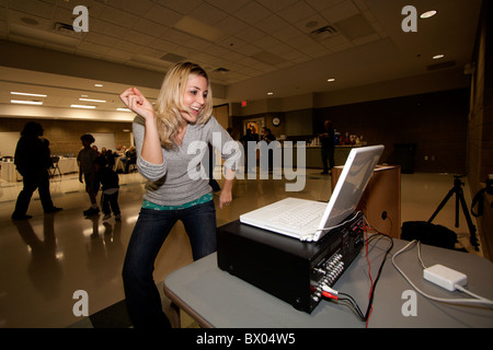 Une femme danse sur la musique à partir d'un ordinateur portable lors d'une fête. Banque D'Images