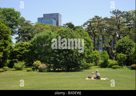 Mère et fille japonaise sur une couverture dans le jardin du Palais Impérial avec tours à l'arrière-plan, Tokyo, Japon Banque D'Images