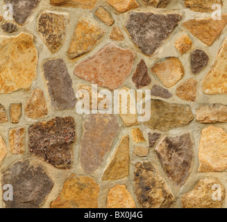 Un mur en maçonnerie avec des pierres de forme irrégulière. La texture se répète à la fois horizontalement et verticalement de manière transparente. Banque D'Images