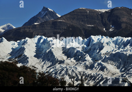 Groupe de randonneurs-glace lointain sur la surface ondulée de l'Perito Moreno Glacier, au-dessous d'une toile de pics rocheux, les Andes Banque D'Images