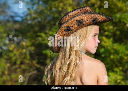 Profil d'une jeune fille avec de longs cheveux blonds portant un chapeau de cowboy, à la recherche sur le côté. Banque D'Images