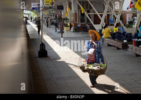 Une femme asiatique portant un chapeau de paille orange est la vente de nourriture pour les passagers du train dans la province d'Ubon Ratchathani, en Thaïlande. Banque D'Images