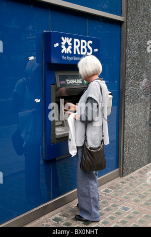 Une femme à la retraite à l'aide d'un distributeur de billets à un distributeur automatique de billets de la Royal Bank of Scotland, dans le centre de Londres. DAVID MANSELL Banque D'Images