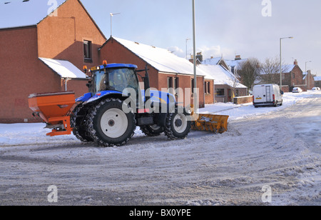 Un tracteur avec chasse-neige neige saleuses efface et se répand le sel dans les rues de la ville. Banque D'Images